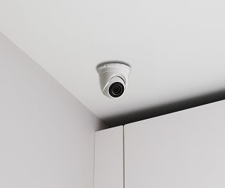 A ceiling-mounted ADT turret camera inside a commercial space, monitoring the area for safety and security. ADT installer and customer in her home