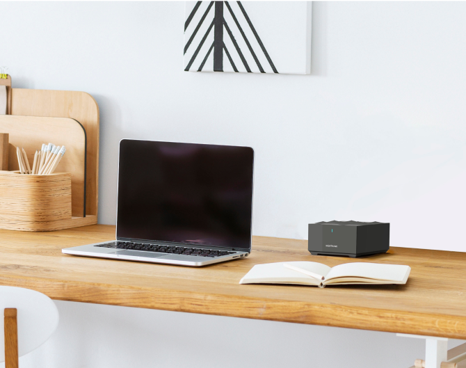 Netgear Mesh WiFi on a wooden desk next to a laptop and notebook Netgear Mesh WiFi on a wooden desk next to a laptop and notebook